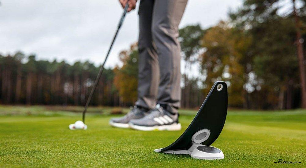 Someone using the a PuttOUT training aid outside.